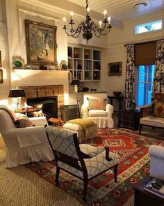 a living room filled with furniture and a fire place under a chandelier in front of a window