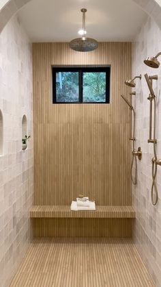 a bathroom with a wooden bench next to a window and shower head mounted on the wall