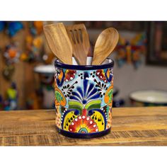 two wooden utensils in a colorful ceramic cup with spoons and fork inside