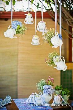 hanging tea kettles filled with flowers on a table