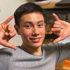 a young man holding his fingers up in the air