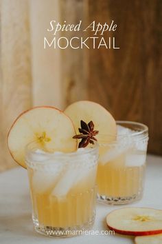 two glasses filled with apple cider cocktails on top of a table next to sliced apples