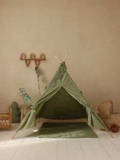 a green teepee tent sitting on top of a white floor next to a wall