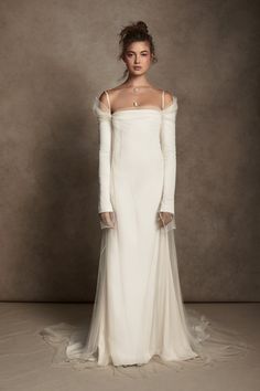 a woman in a white wedding dress with long sleeves and an off the shoulder neckline