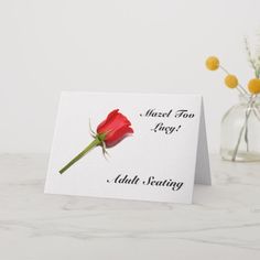 a red rose sitting on top of a table next to a vase filled with flowers