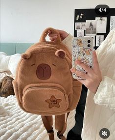 a person holding up a brown teddy bear backpack