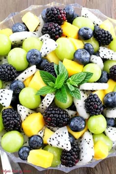 a fruit salad with grapes, kiwis, mangoes and blackberries in a bowl