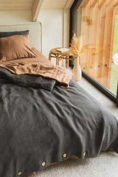 a bed sitting in a bedroom next to a window with a vase on top of it