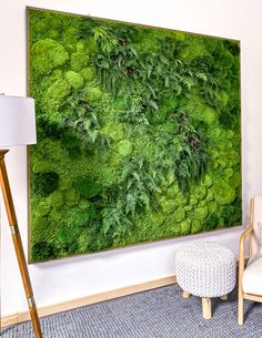 a living room with a large moss wall hanging on the wall next to a chair