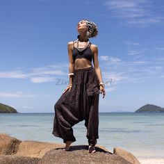 a woman standing on top of a rock next to the ocean with her eyes closed