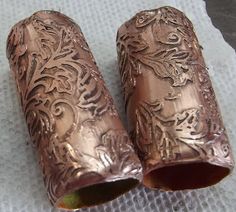 two copper vases sitting on top of a white cloth