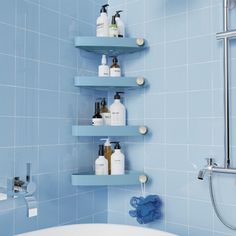 a blue tiled bathroom with shelves holding personal care products on the wall and in the bathtub