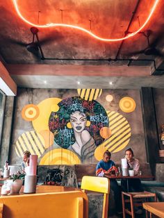 people sitting at tables in front of a mural