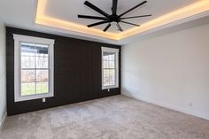 an empty room with two windows and a ceiling fan in the center of the room