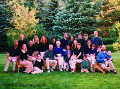 a large group of people are posing for a photo in the grass with trees behind them