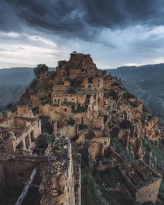 an old village on top of a mountain under a cloudy sky with dark clouds in the background