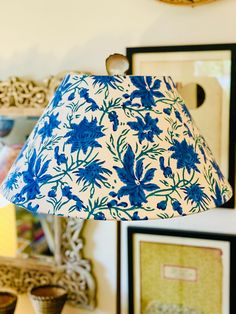 a blue and white lamp sitting on top of a wooden table next to framed pictures