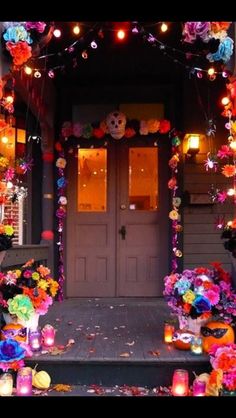 halloween decorations on the front steps of a house with candles and flowers in pots outside