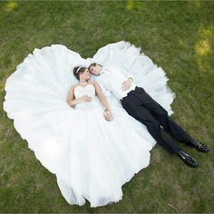 a bride and groom laying on the grass