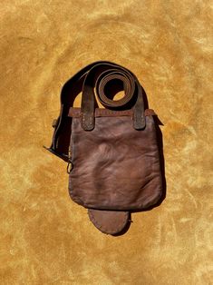 a brown leather bag is laying on the ground with a strap hanging from it's side