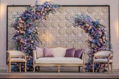 a couch and two chairs in front of a wall with flowers