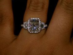 a close up of a person's hand with an engagement ring on their finger