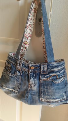 an old pair of jeans hanging from a hook on a door handle with a flowered ribbon