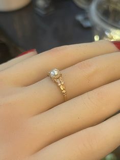 a woman's hand with a pearl ring on it