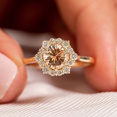 a close up of a person holding a ring with a brown diamond in the middle