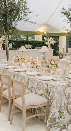 a table set up for an event with flowers and candles on the tables in front of it