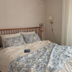 a bed with blue and white comforter in a bedroom next to a window,