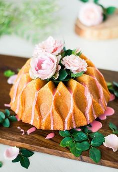 a bundt cake with pink icing and flowers on it sitting on a cutting board