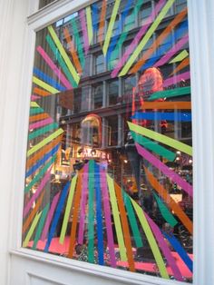 a store window with multicolored ribbons in it's windows display the building across the street