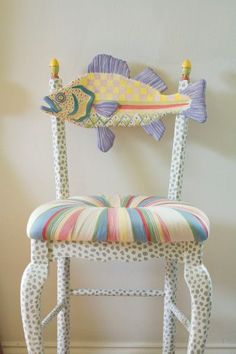 a chair with a fish on the back and colorful fabric seat padding, sitting in front of a white wall