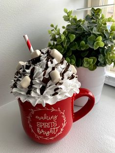 a red cup filled with chocolate and marshmallows next to a potted plant