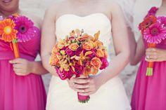 three bridesmaids in pink dresses holding bouquets with orange and pink flowers on them