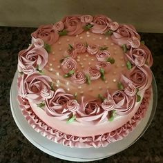 a cake with pink frosting and roses on top is sitting on a countertop