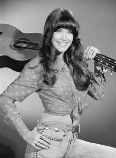 an old photo of a woman with a guitar in her hand and smiling at the camera