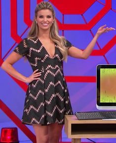 a woman standing in front of a laptop computer on a desk with her hands out