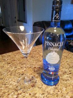 two martini glasses sitting on top of a counter next to a bottle of pinnacle vodka