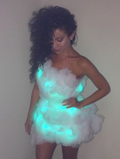 a woman in a white dress with green lights on her chest and arms behind her back