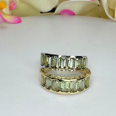 two gold rings sitting on top of a white table next to pink and white flowers