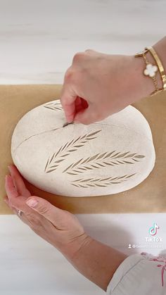 a woman is carving a rock with leaves on it