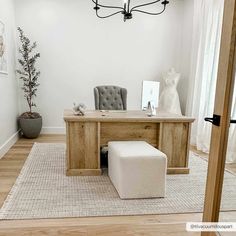 a room with a desk, chair and ottoman on the floor in front of a window