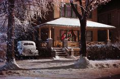 an old car is parked in front of a house with christmas decorations on the porch