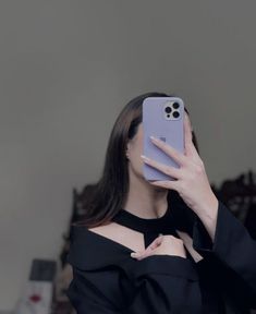 a woman taking a selfie with her cell phone in front of her face while wearing a black top