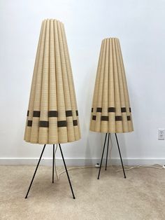 two lamps made out of bamboo with black lines on them, sitting next to each other