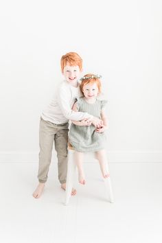 two children sitting on a chair with their arms around each other