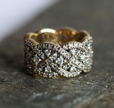 a close up of a gold ring with diamonds on it's sides, sitting on a stone surface