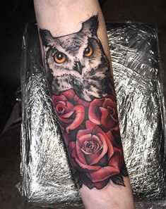 an owl and roses tattoo on the arm is shown in black and grey colors with orange eyes